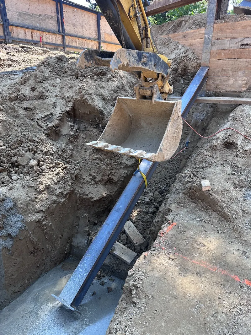 Steel raker being positioned in an excavation with an excavator